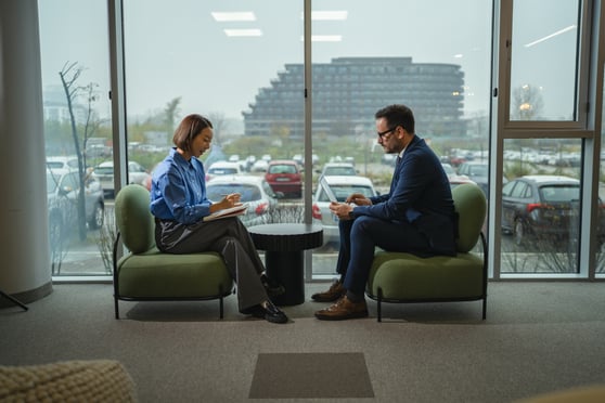 Professionals sitting in a modern office space with a notebook and a laptop