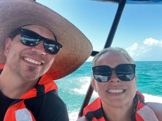 A WSI consultant and his family wearing sunglasses and life jackets on a boat, with bright turquoise ocean water in the background.